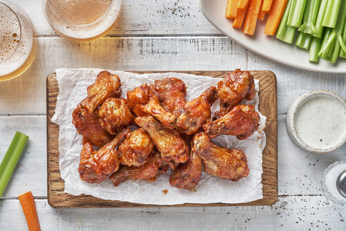Overhead view of chicken wings, carrot, and celery sticks on a plate.