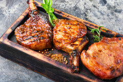 grilled pork chops on wooden cutting board